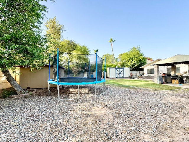 view of yard featuring a trampoline and a shed