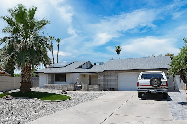 ranch-style house with a garage and solar panels