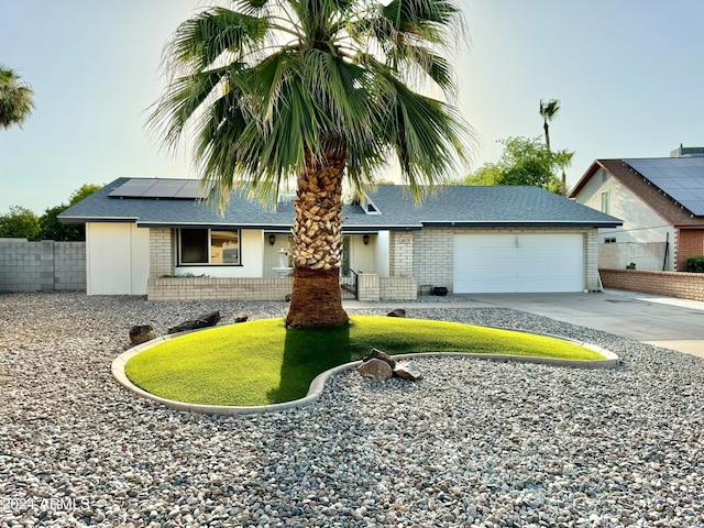 ranch-style home with a garage and solar panels