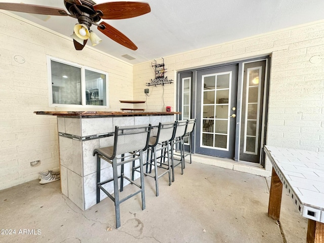 interior space featuring ceiling fan and a bar