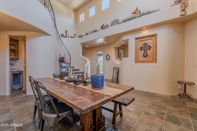 8606 E Arroyo Seco Rd, Scottsdale, AZ 85266 - dining space with beverage cooler, stairway, stone finish flooring, bar area, and a high ceiling