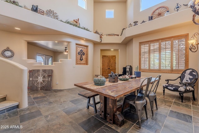 8606 E Arroyo Seco Rd, Scottsdale, AZ 85266 - dining area featuring stone finish flooring, a towering ceiling, healthy amount of natural light, and a ceiling fan