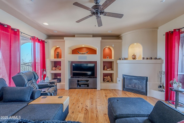 8606 E Arroyo Seco Rd, Scottsdale, AZ 85266 - living area featuring a glass covered fireplace, wood-type flooring, ceiling fan, and built in features