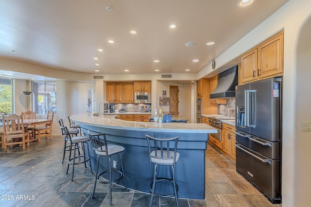 8606 E Arroyo Seco Rd, Scottsdale, AZ 85266 - kitchen featuring high quality appliances, wall chimney exhaust hood, recessed lighting, a large island with sink, and a kitchen bar