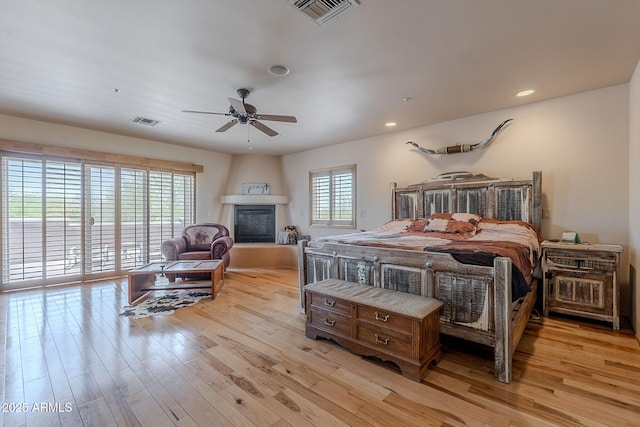 8606 E Arroyo Seco Rd, Scottsdale, AZ 85266 - bedroom with light wood-style flooring, a large fireplace, recessed lighting, and a ceiling fan
