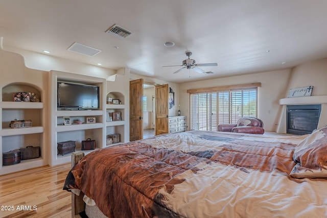 8606 E Arroyo Seco Rd, Scottsdale, AZ 85266 - bedroom with light wood finished floors, a glass covered fireplace, recessed lighting, and a ceiling fan