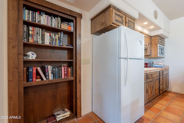 8606 E Arroyo Seco Rd, Scottsdale, AZ 85266 - kitchen featuring freestanding refrigerator, stainless steel microwave, brown cabinetry, recessed lighting, and light countertops