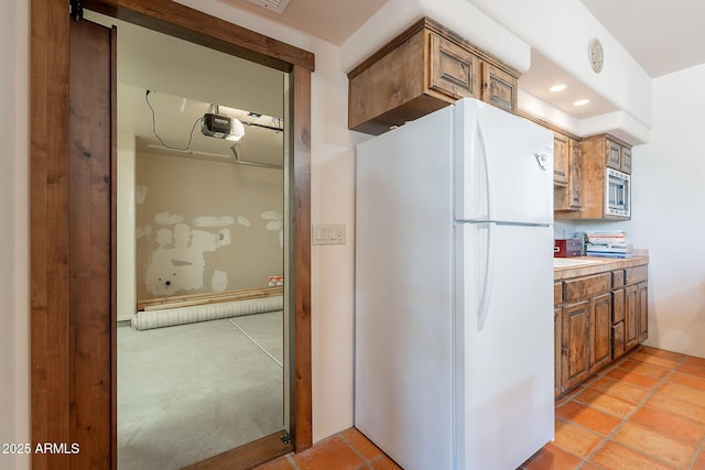 8606 E Arroyo Seco Rd, Scottsdale, AZ 85266 - kitchen with freestanding refrigerator, brown cabinetry, stainless steel microwave, recessed lighting, and light countertops
