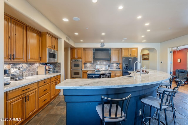 8606 E Arroyo Seco Rd, Scottsdale, AZ 85266 - kitchen featuring appliances with stainless steel finishes, a sink, a large island, arched walkways, and tasteful backsplash