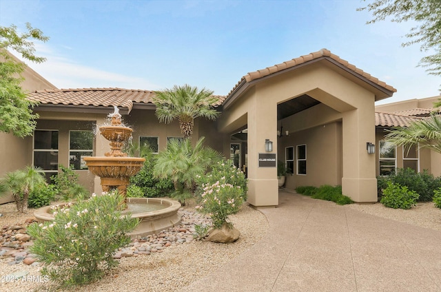 rear view of property featuring a tiled roof and stucco siding