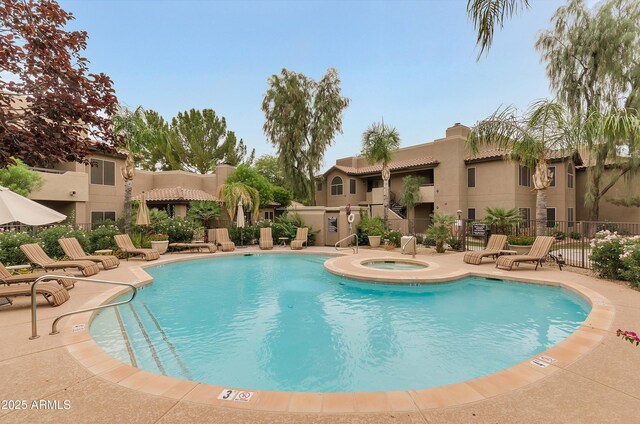 pool featuring a community hot tub, a patio area, and fence