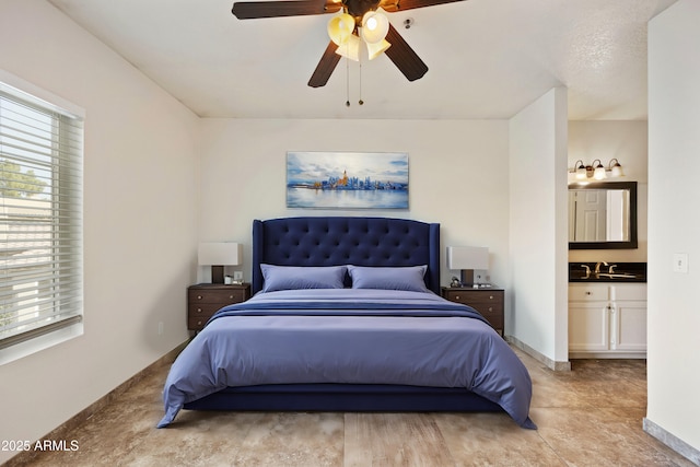 bedroom with ensuite bath, baseboards, and a ceiling fan