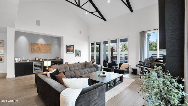 living room with wine cooler, light wood-type flooring, high vaulted ceiling, and a wealth of natural light