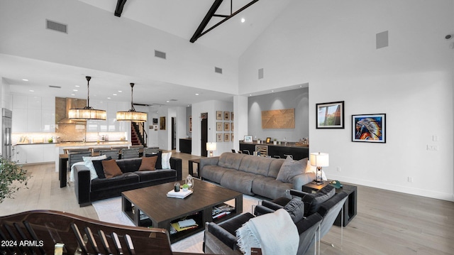 living room with high vaulted ceiling, a chandelier, and light hardwood / wood-style floors