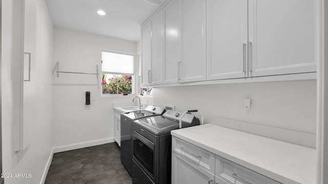 laundry room featuring dark tile patterned floors, cabinets, sink, and washing machine and clothes dryer