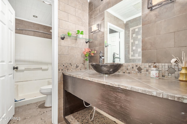 bathroom with tile walls, a tile shower, toilet, vanity, and tile floors