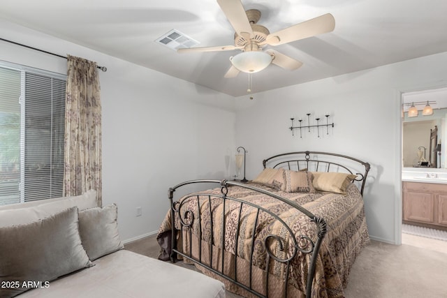 bedroom with ensuite bathroom, sink, light carpet, and ceiling fan