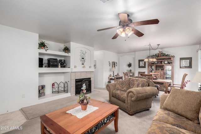 carpeted living room with a tile fireplace and ceiling fan