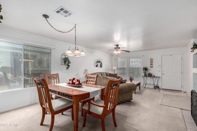 dining room with ceiling fan with notable chandelier and light colored carpet