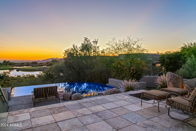 patio terrace at dusk featuring a water view