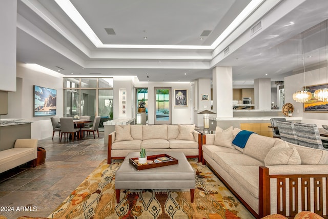 living room featuring a tray ceiling and a notable chandelier