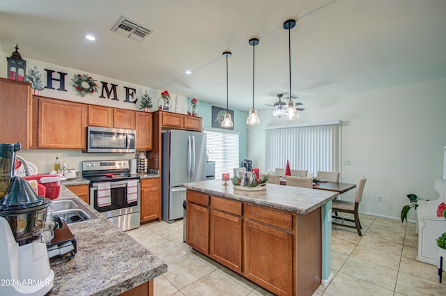 kitchen with ceiling fan, hanging light fixtures, stainless steel appliances, light tile patterned floors, and a kitchen island