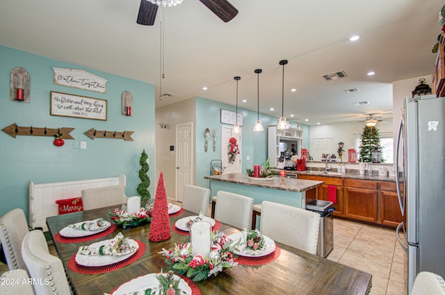 tiled dining room with ceiling fan and sink