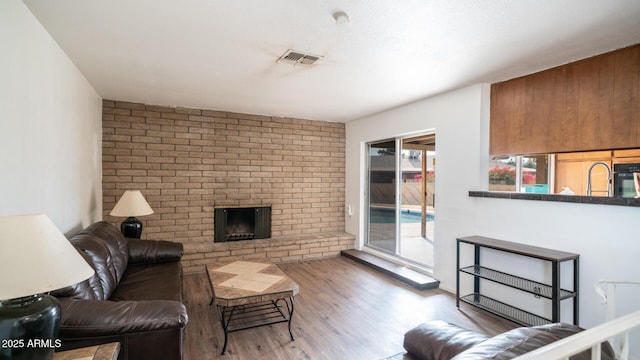 living room featuring hardwood / wood-style flooring and a brick fireplace