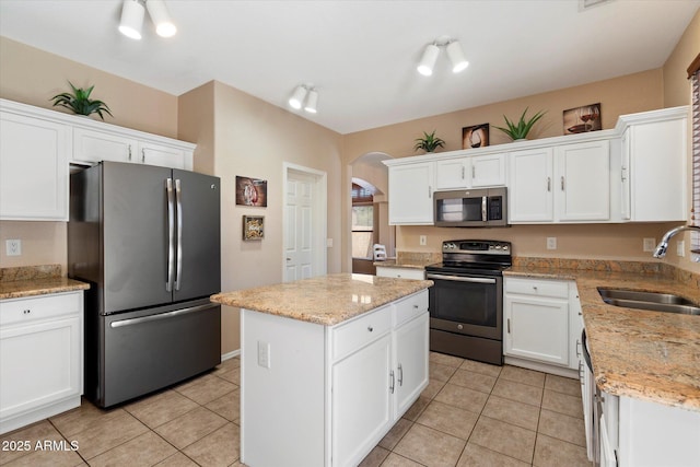 25818 N 68th Ave, Peoria, AZ 85383 - kitchen with stainless steel appliances, arched walkways, a kitchen island, white cabinetry, and light tile patterned floors