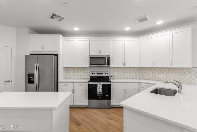 kitchen with sink, appliances with stainless steel finishes, white cabinetry, tasteful backsplash, and light wood-type flooring