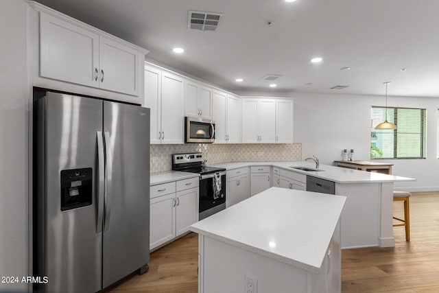 kitchen with stainless steel appliances, pendant lighting, white cabinets, and kitchen peninsula