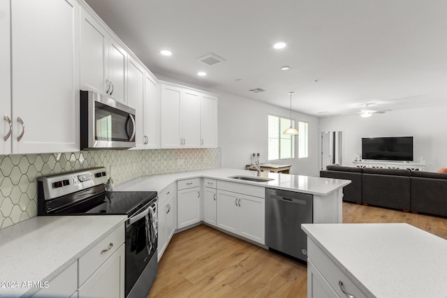 kitchen featuring white cabinetry, appliances with stainless steel finishes, sink, and decorative light fixtures