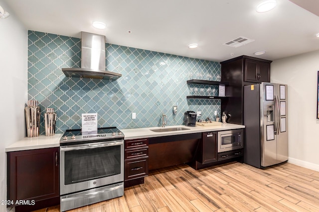 kitchen with light wood-type flooring, stainless steel appliances, sink, and wall chimney range hood