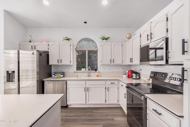 kitchen featuring appliances with stainless steel finishes, white cabinetry, light countertops, and a sink