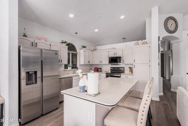 kitchen featuring stainless steel appliances, a kitchen island, wood finished floors, and light countertops