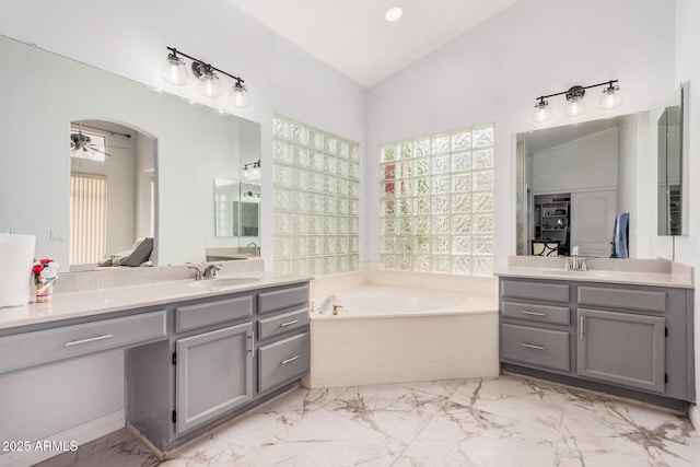 full bathroom with ceiling fan, a garden tub, two vanities, lofted ceiling, and a sink