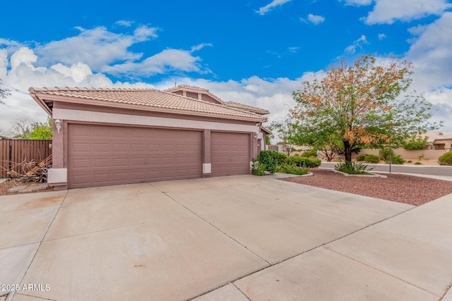 garage featuring concrete driveway and fence