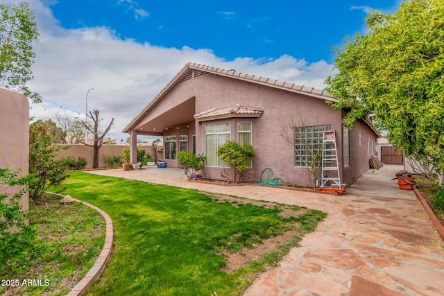 rear view of property with stucco siding, a patio, a lawn, and a fenced backyard