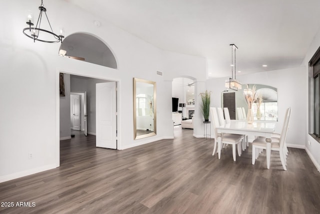 dining room featuring a chandelier, arched walkways, baseboards, and dark wood-style flooring