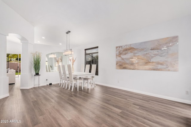 unfurnished dining area with baseboards, arched walkways, and wood finished floors