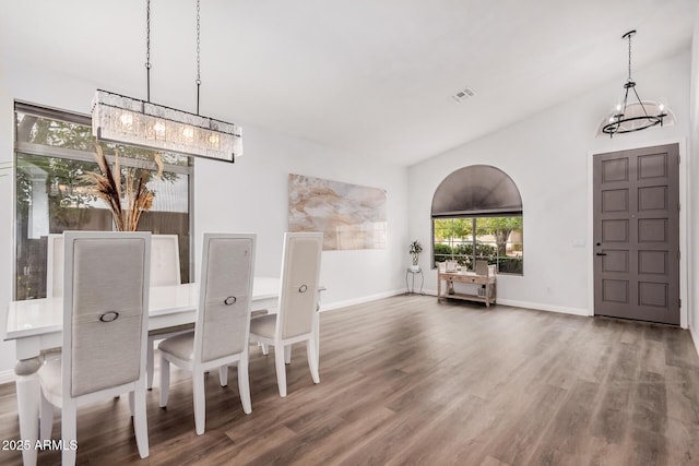 dining room with wood finished floors, visible vents, baseboards, an inviting chandelier, and lofted ceiling