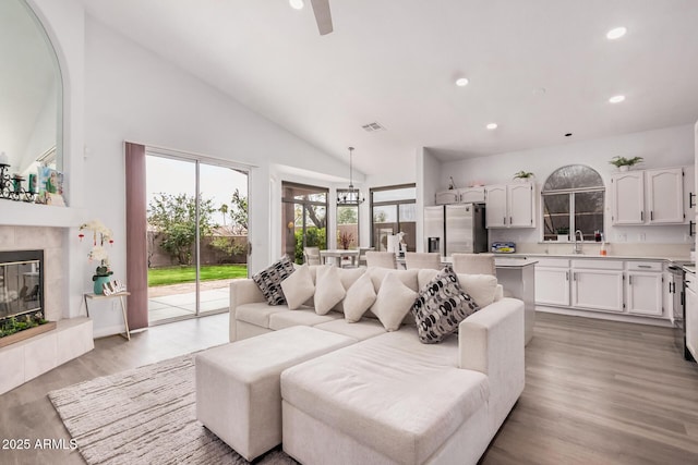 living room featuring visible vents, recessed lighting, ceiling fan, a tile fireplace, and light wood-type flooring