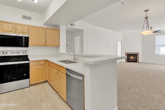 kitchen featuring stainless steel appliances, kitchen peninsula, sink, and light brown cabinets