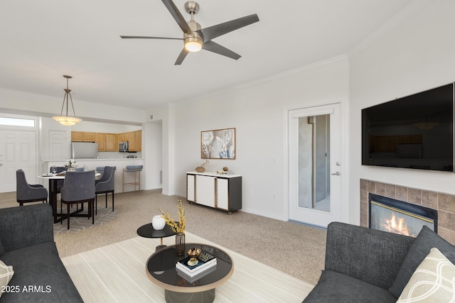 carpeted living room with ceiling fan, ornamental molding, and a tile fireplace