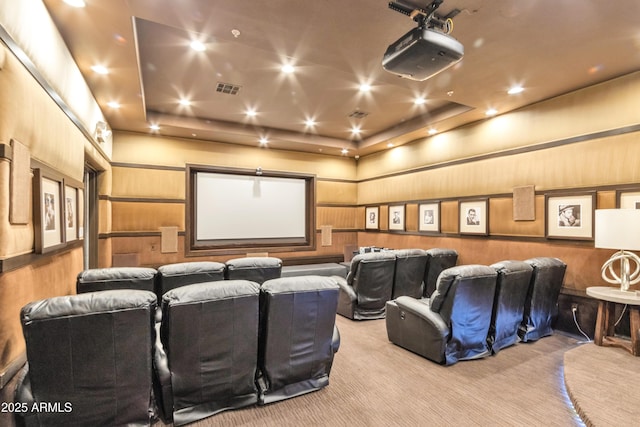 home theater with light colored carpet, wooden walls, and a raised ceiling