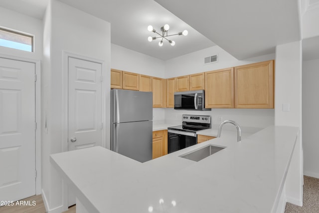 kitchen featuring sink, appliances with stainless steel finishes, kitchen peninsula, a chandelier, and light brown cabinets