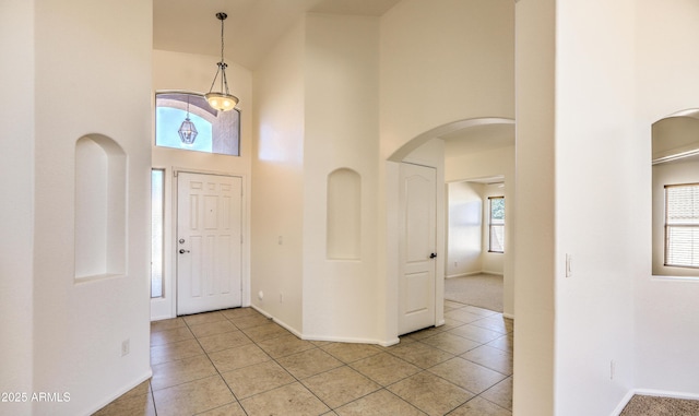 17617 W Corrine Dr, Surprise, AZ 85388 - foyer entrance featuring a towering ceiling, arched walkways, baseboards, and light tile patterned floors