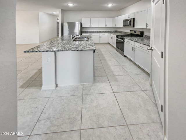 kitchen featuring dark stone counters, a center island with sink, white cabinets, sink, and appliances with stainless steel finishes