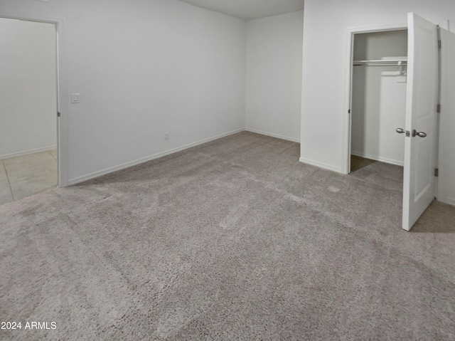 unfurnished bedroom featuring light colored carpet and a closet