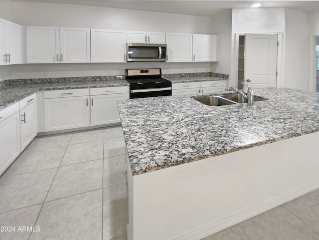 kitchen with white cabinets, appliances with stainless steel finishes, a center island with sink, and sink